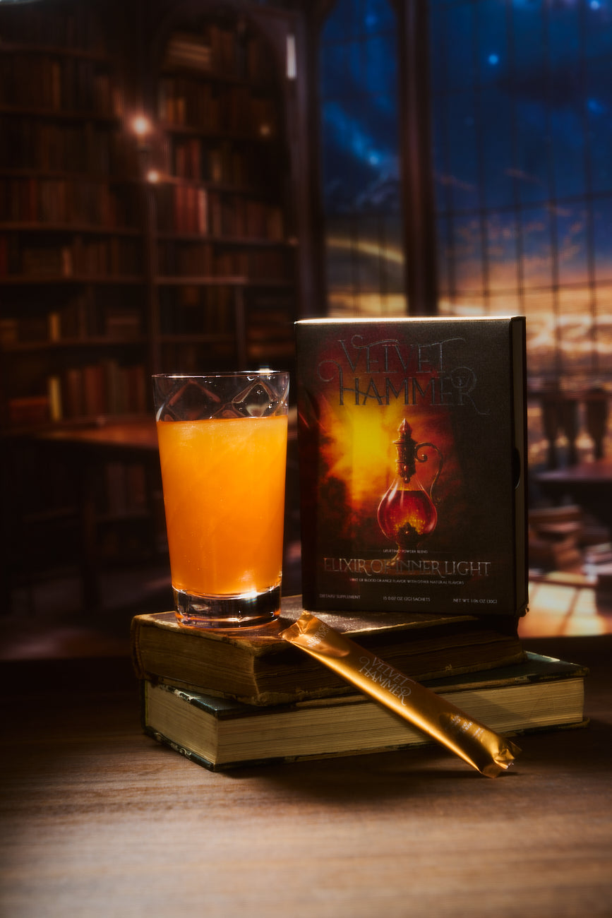 A tall glass of orange Elixir of Inner Light beside its box on a stack of old books, in a library at dusk